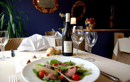 a table with a plate of food and a bottle of wine at Demians in Saldus
