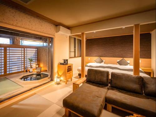 a bedroom with a couch and a bed and a tub at 割烹旅館 清都 in Hongō