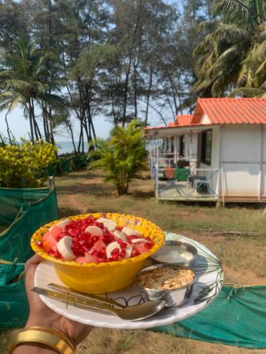 uma pessoa segurando uma tigela de comida em uma mesa em Nikhils Luxury Beach Cottages em Magdāl