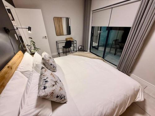 Luxury Coastal Escape in Strand في Somerset West: غرفة نوم بسرير أبيض مع نافذة كبيرة