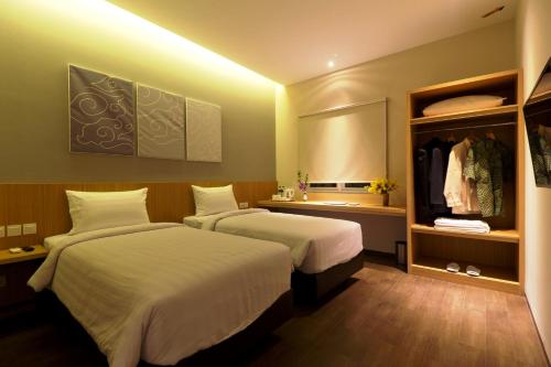 a hotel room with two beds and a closet at Vinotel Cirebon in Cirebon