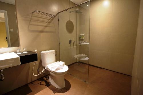 a bathroom with a toilet and a glass shower at Vinotel Cirebon in Cirebon