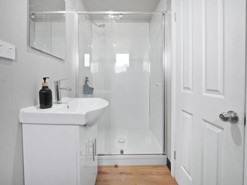 a white bathroom with a sink and a shower at Parkes Cabins in Parkes