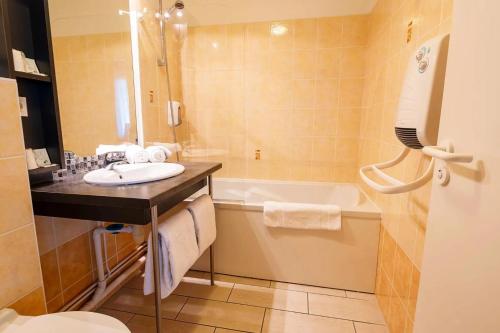 un bagno con lavandino e vasca da bagno di Hotel L'Océane Angers Parc Expo a Saint-Sylvain-dʼAnjou