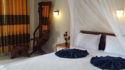 a bedroom with a white bed with blue pillows at Sigiri Lion Lodge in Sigiriya