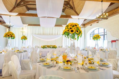 a wedding reception with white tables and chairs and sunflowers at Pałac Łagów in Zgorzelec