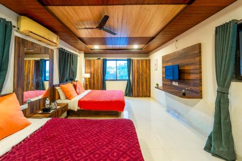 a hotel room with two beds and a tv at Strawberry County in Panchgani