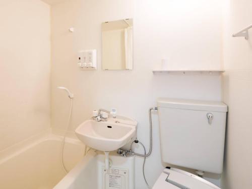 a white bathroom with a toilet and a sink at Comfort Inn Yokaichi in Higashiomi