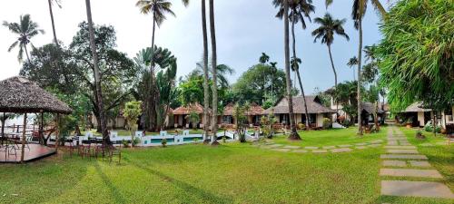 a resort yard with a swimming pool and palm trees at Les 3 Elephants in Cherai Beach