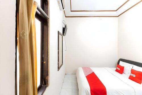 um quarto com uma cama com almofadas vermelhas e uma janela em Hotel O Wisma Pelita Mas em Pampang