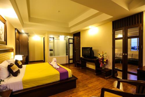 a hotel room with a bed and a television at Madina Rayong Hotel in Rayong