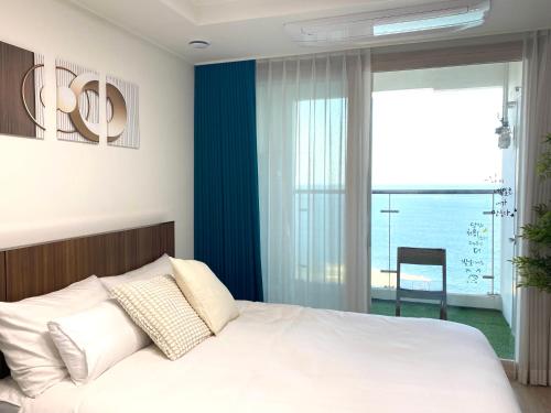 a bedroom with a bed with a view of the ocean at 속초 오션뷰 써밋베이1205 in Sajin