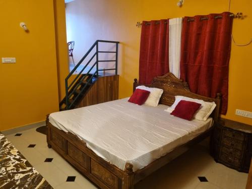 een slaapkamer met een bed met rode gordijnen en een trap bij Loto Villa in Bangalore