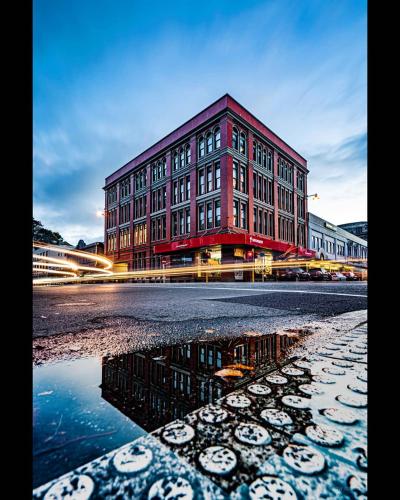 a large red building with a reflection in the water at The Chamberson in Dunedin
