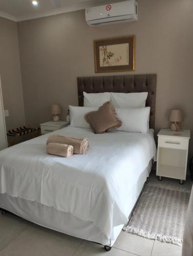 a bedroom with a white bed with two towels on it at Die Stoep in Richards Bay