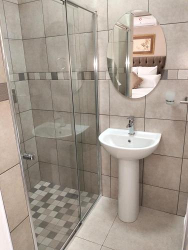 a bathroom with a sink and a shower with a mirror at Die Stoep in Richards Bay