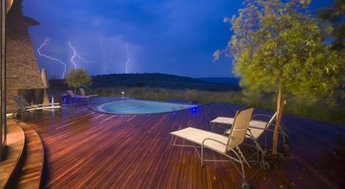 a deck with chairs and a swimming pool with lightning at Maropeng Boutique Hotel in Magaliesburg