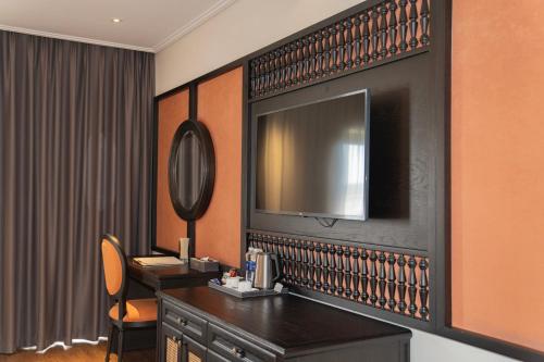 ein Hotelzimmer mit einem Schreibtisch und einem TV an der Wand in der Unterkunft Green Dragon Boutique Hotel in Cẩm Phả