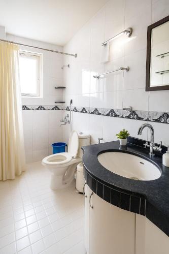 a white bathroom with a sink and a toilet at Navilehomestay in Candolim