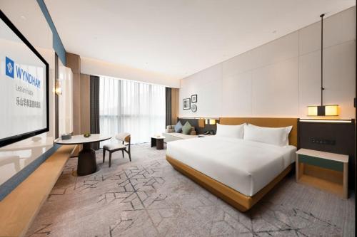 a hotel room with a large bed and a desk at Wyndham Leshan Downtown in Leshan