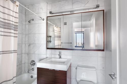 a white bathroom with a sink and a mirror at Tribeca Studio w Pool Gym View nr City Hall NYC-312 in New York
