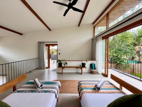 zwei Betten in einem Zimmer mit großen Fenstern in der Unterkunft Villa Luna - Gili Air in Gili Air
