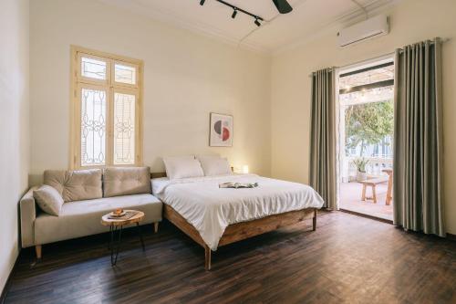 a bedroom with a bed and a couch and a window at Glass Apartment With Big Balcony in Hanoi