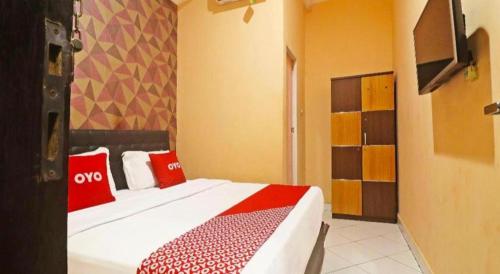 una camera da letto con un letto con cuscini rossi di Hotel O Papi Inn Guesthouse a Palangkaraya