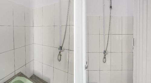 ein weiß gefliestes Badezimmer mit Dusche und Toilette in der Unterkunft Hotel O 3m Kost Dan Homestay in Paniki-atas