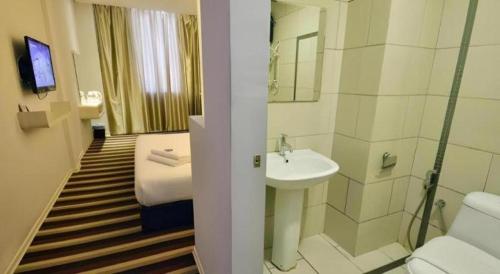 una camera d'albergo con bagno dotato di letto e lavandino di First Residence Hotel Kemaman a Kampong Gong Pauh