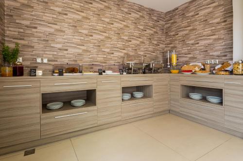 een keuken met houten kasten en een bakstenen muur bij Romantica Hotel in Georgioupolis
