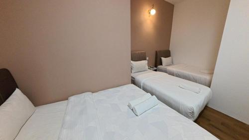 two beds in a small room with white sheets at Nice Inn in George Town