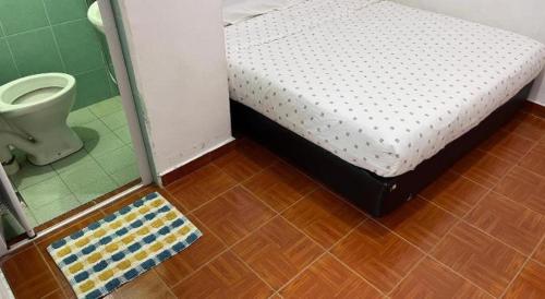 a small bedroom with a bed and a toilet at OYO 89928 ACF Guest House in Sungai Lembing