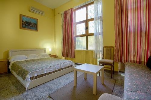 um quarto com uma cama, uma mesa e uma janela em B&B Klub 011 em Belgrado