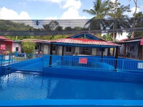 ein Gebäude mit einem blauen Zaun um einen Swimmingpool in der Unterkunft OYO Home 90554 Norfa Camp House in Kampong Tanah Baharu
