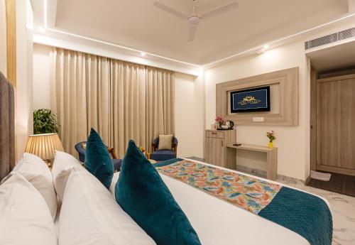 a hotel room with a large bed with blue pillows at Hotel The Grand Bharath in New Delhi