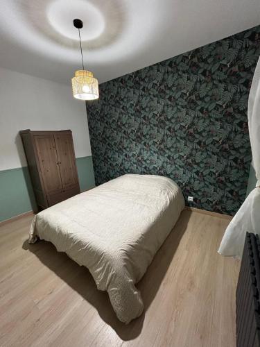 Un dormitorio con una cama con una pared verde. en Au Papillon, en Magenta