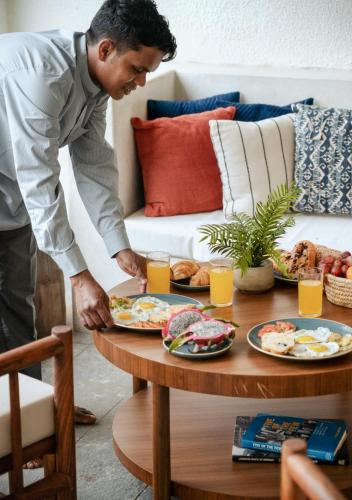 LohonoStays Villa Beleza C في Oxel: رجل يقف أمام طاولة مع أطباق من الطعام