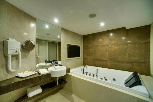 a bathroom with a bath tub and a sink and a bath tub at Ramee Guestline Hotel Juhu in Mumbai