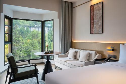 HaihuiにあるGuanyun Manxin Mansion, Guling, Lushanのベッドとソファとテーブルのあるホテルの部屋