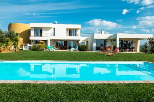 a villa with a swimming pool in front of a house at Amazing Windmillhouses in Olhão