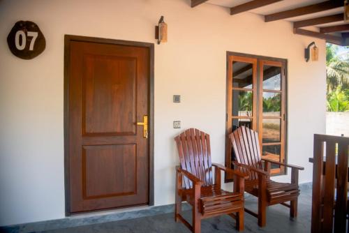Wilpattu Wild Cottages في Nochchiyagama: كرسيين خشبيين جالسين امام باب