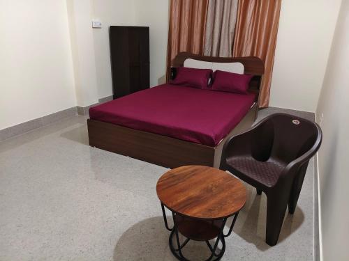 a bedroom with a bed and a chair and a table at JM Niwas in Guwahati