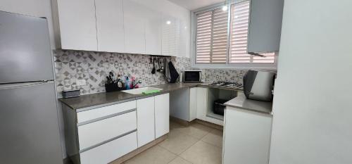 a kitchen with white cabinets and a refrigerator at Modern Family Apartment by IsrApart in H̱olon