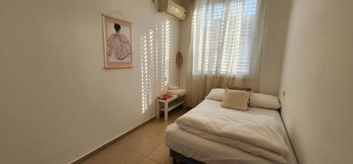 a small bedroom with a small bed and a window at Modern Family Apartment by IsrApart in H̱olon