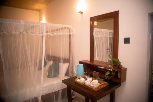Wilpattu Wild Cottages في Nochchiyagama: حمام مع مرآة وطاولة مع حوض