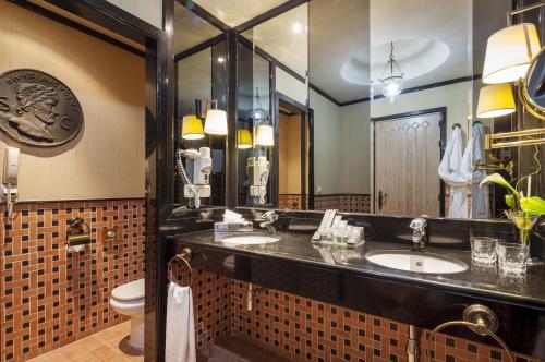 a bathroom with two sinks and a toilet at Hotel Ilunion Mérida Palace in Merida