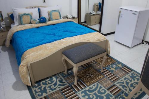 a bedroom with a bed with a blue blanket and a stool at Hill View Hotel McCarthy Hills in Bortianor
