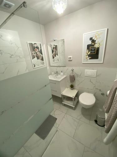 a white bathroom with a toilet and a sink at LadyM in Rabac