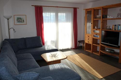 Ferienhaus Nr 124, Kategorie Economy, Feriendorf Hochbergle, Allgäu في Karlsebene: غرفة معيشة مع أريكة زرقاء وتلفزيون